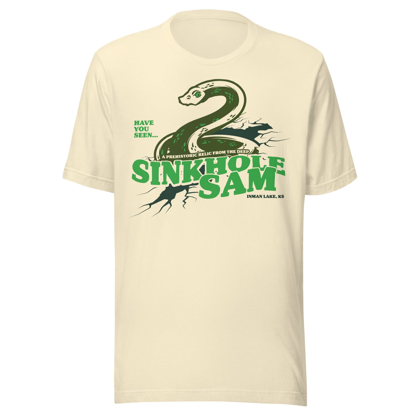 Cream-colored T-shirt with a green snake-like cryptid emerging from cracked earth, with the text ‘Sinkhole Sam – A Prehistoric Relic from the Deep, Inman Lake, KS.’