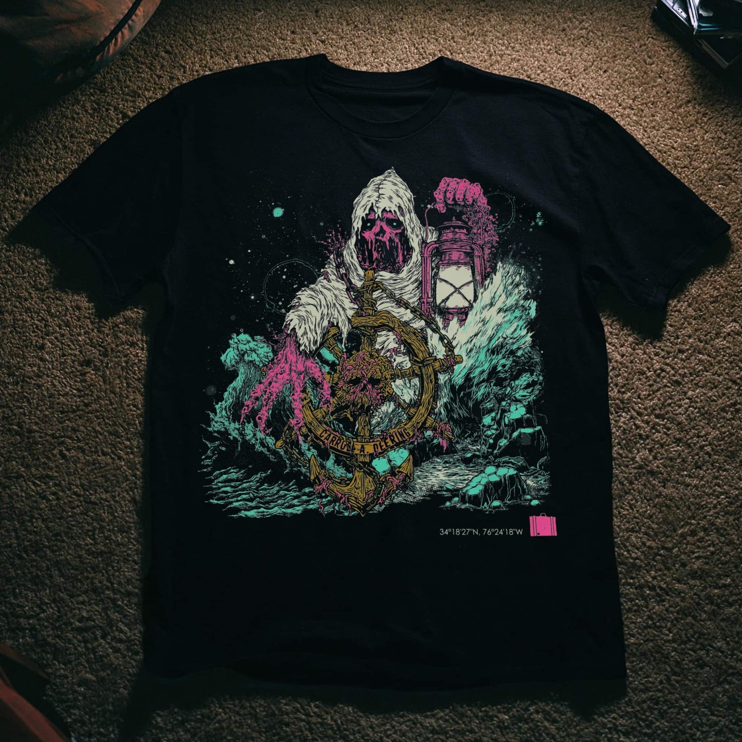 Horror art t-shirt featuring a skeletal phantom helmsman gripping the wheel of the Carroll A. Deering ghost ship, surrounded by crashing waves and tentacles, with Cape Hatteras coordinates, on black.